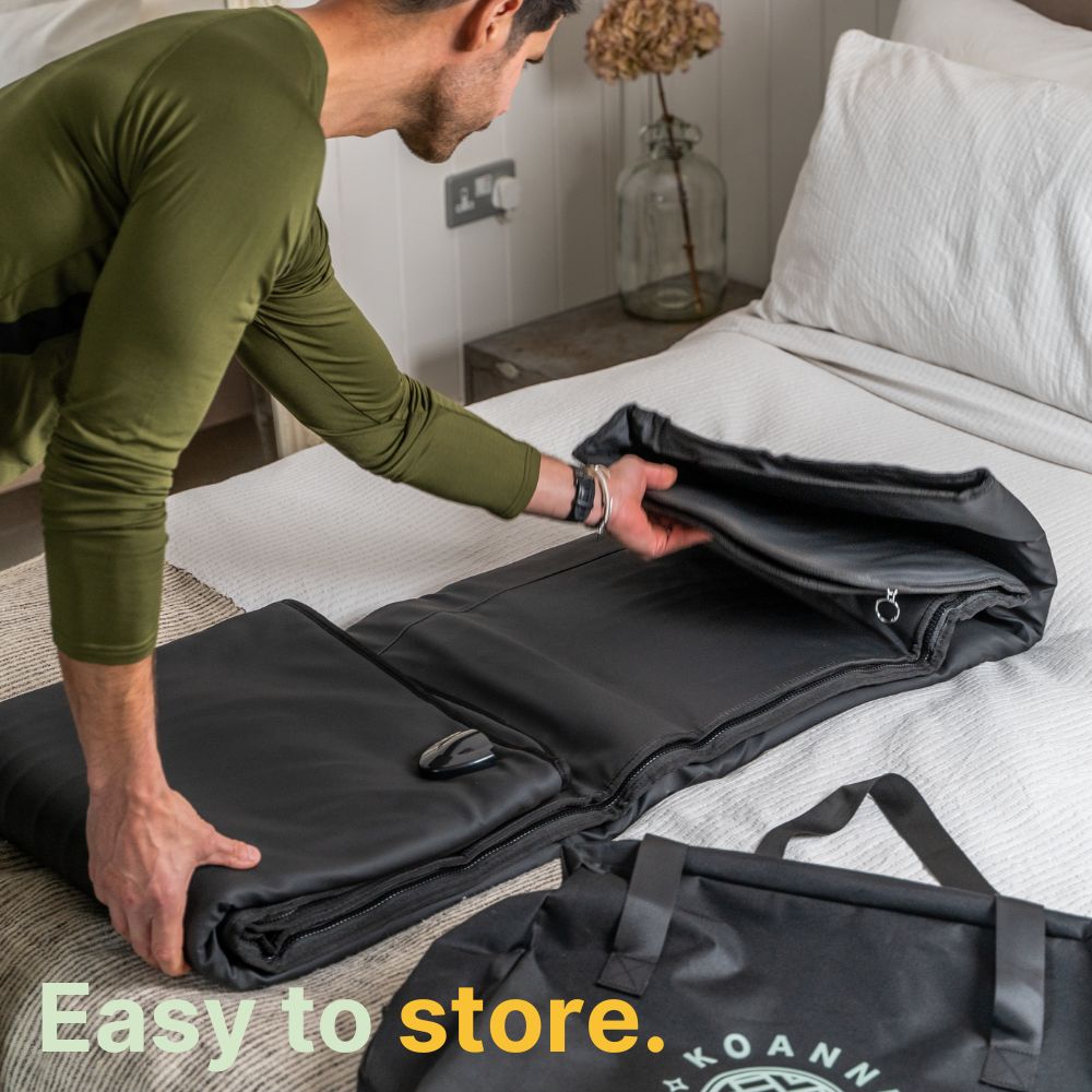 Middle-aged man folds the black sauna blanket to put it in its travel bag.