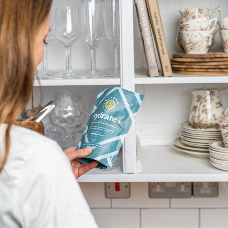 Woman standing in the kitchen looking at the Hydrate+ package.