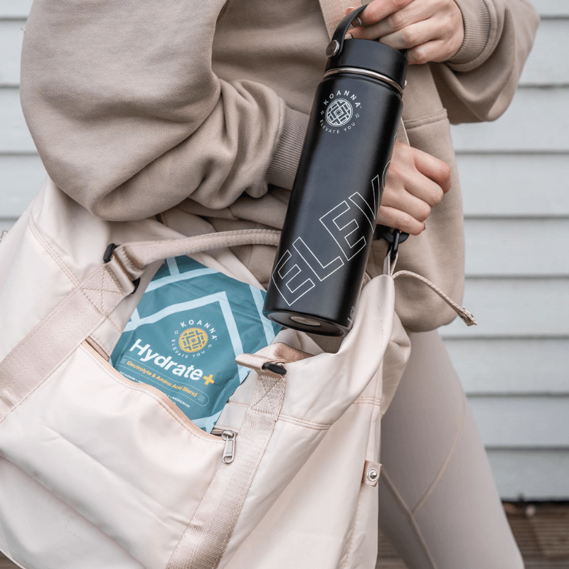 A woman on the go with Hydrate+ in her bag and an Elevate bottle in her hand.